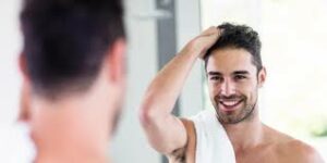 Man standing in front of mirror rubbing hand through hair 